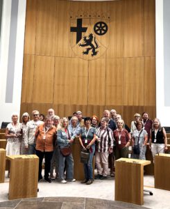 2026 09 Landtag - Omas for Future Eine große Gruppe von Menschen, die vor einer Holzwand mit einem Wappen für ein Foto posiert.
