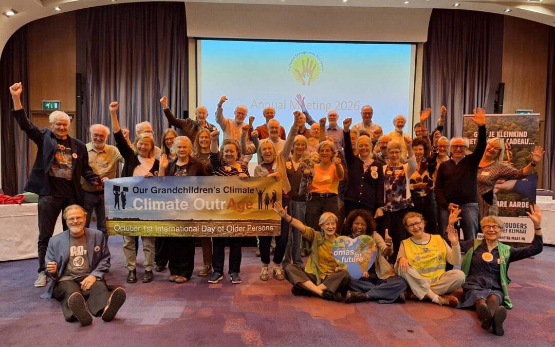 Eine große Gruppe älterer Menschen posiert in einem Konferenzraum für ein Foto und hält dabei ein Transparent mit der Aufschrift Our Grandchildren’s Climate OutrAge – am 1. Oktober, dem Internationalen Tag der älteren Menschen.