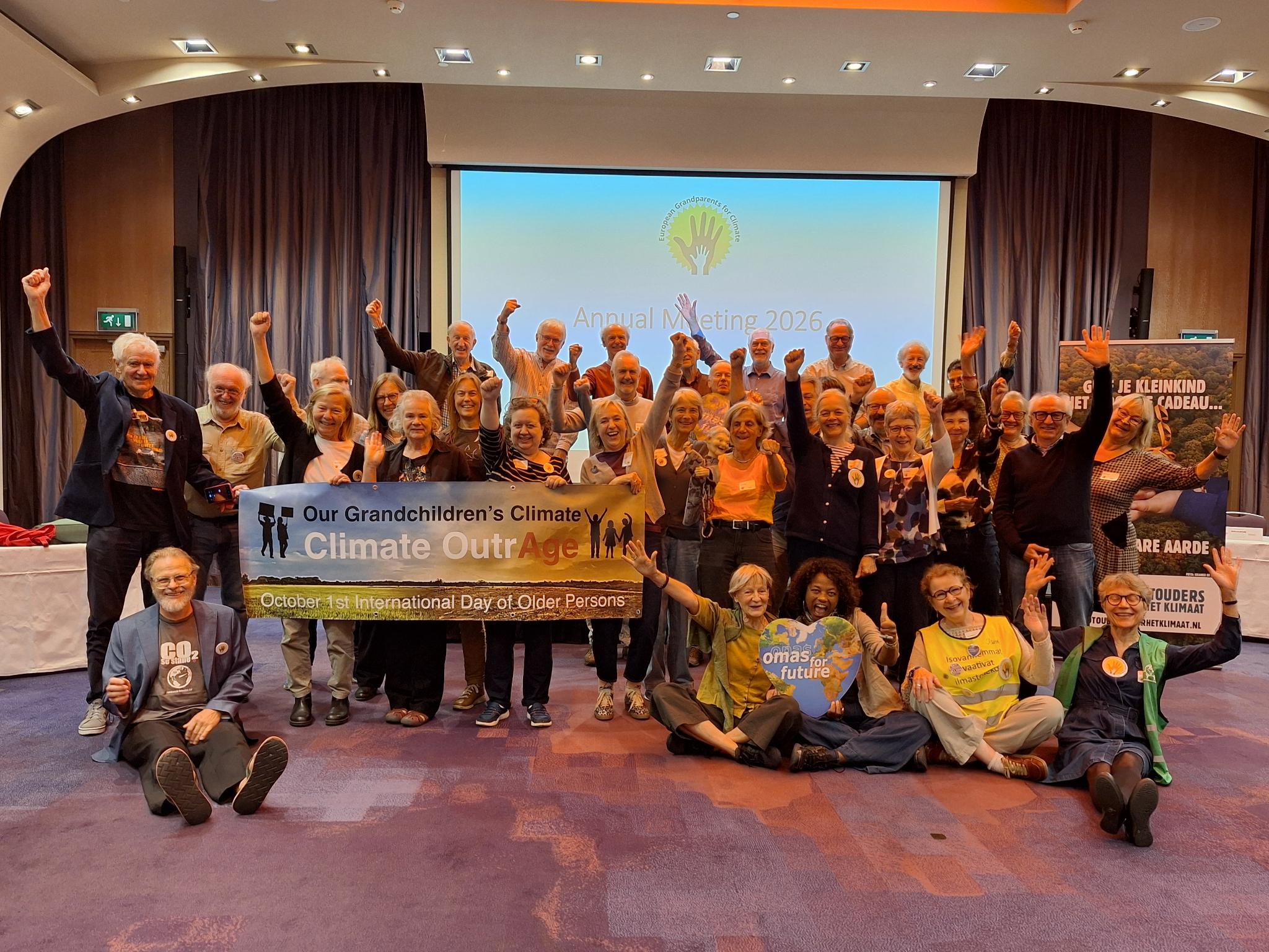 Eine große Gruppe älterer Menschen posiert in einem Konferenzraum für ein Foto und hält dabei ein Transparent mit der Aufschrift Our Grandchildren’s Climate OutrAge – am 1. Oktober, dem Internationalen Tag der älteren Menschen.