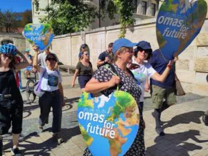 Eine Gruppe von Menschen marschiert unter freiem Himmel in Bad Kreuznach und hält große herzförmige Schilder mit einer Weltkugel und der Aufschrift omas for future. Sie scheinen an einer Klima- oder Umweltdemonstration an einem sonnigen Tag teilzunehmen.