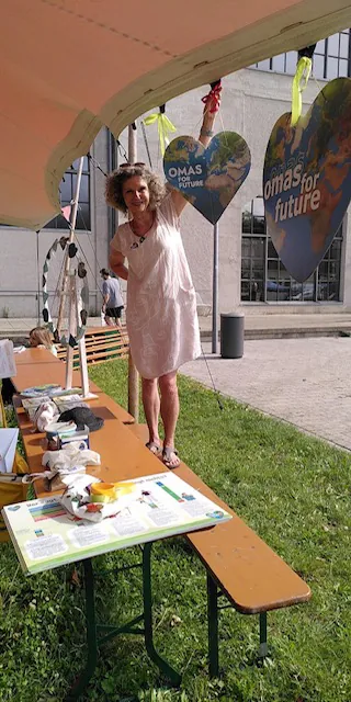 Mitglied der Omas for Future München dekoriert Herz-Banner am Infostand im Freien